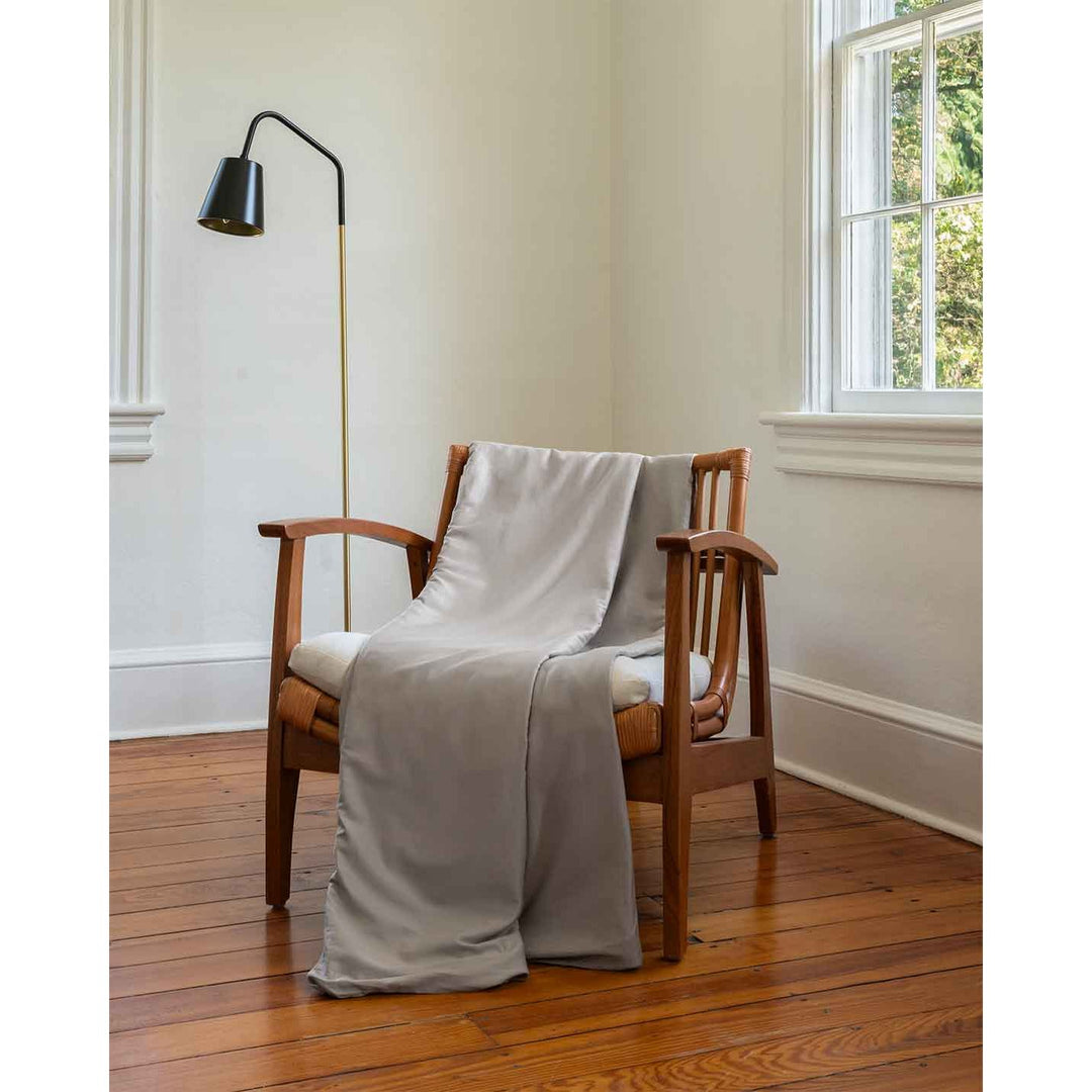 A silver sage cotton duvet cover is folded and placed over the back of a chair in a bedroom [44422682050779, 45027099771099]