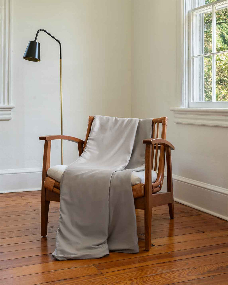 A cotton duvet thrown over a chair next to a lamp [46063268298971, 46301204906203, 46061921468635, 46301205168347, 46061921337563, 46301205037275, 46061921599707, 46061921730779, 46301205299419, 46730786635995, 46730786898139, 46730787160283, 46730787422427]