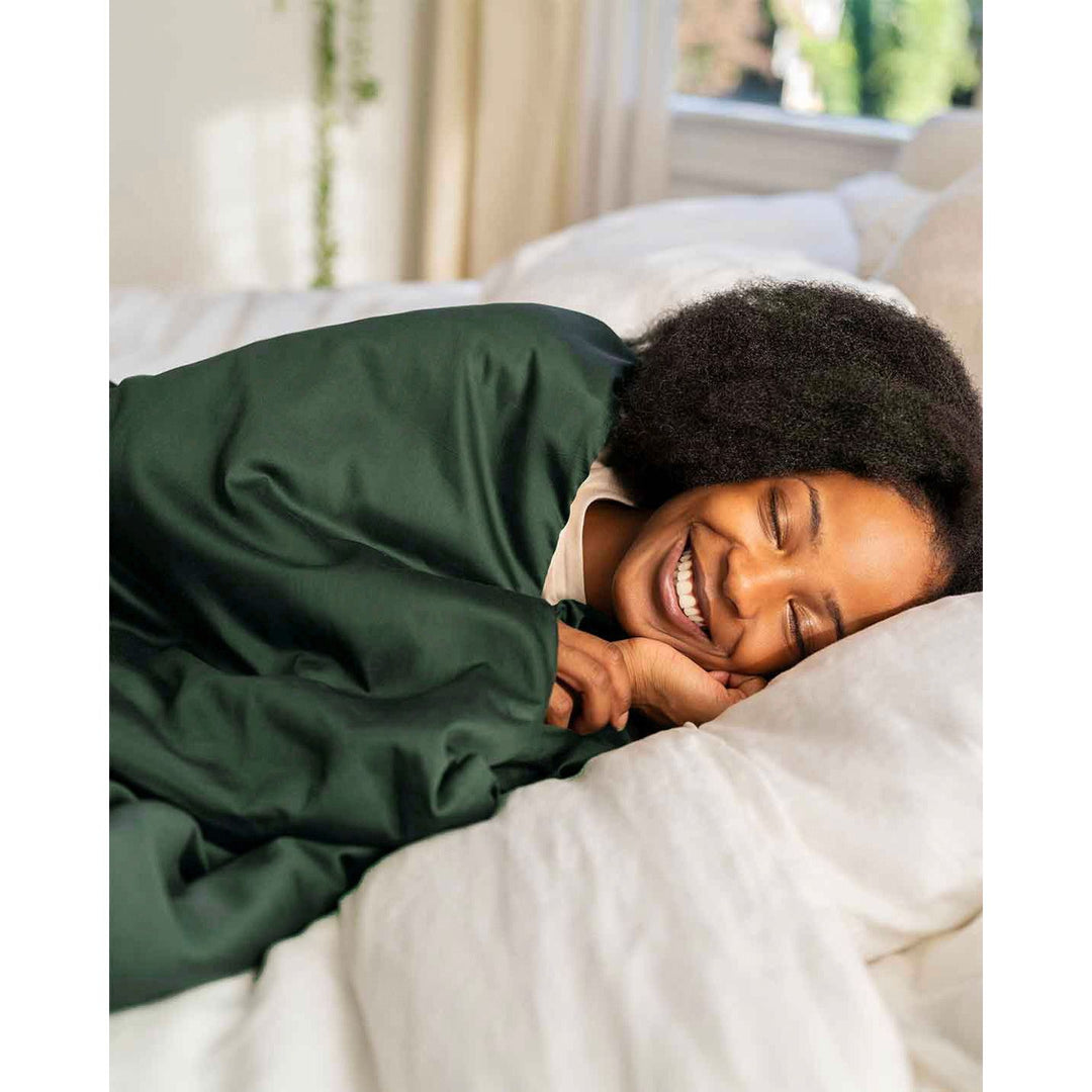 A smiling woman with eyes closed wrapped in a weighted throw with a spruce cotton cover [44422682116315]