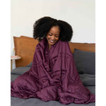 Load image into Gallery viewer, A woman sitting in bed smiles down with a weighted blanket wrapped around her shoulders. [44405994029275, 45574417907931]
