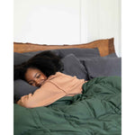 Load image into Gallery viewer, A woman smiles with eyes closed, hugging a pillow under a spruce green weighted blanket [44422820561115, 45574418333915, 44422814826715, 46452818542811, 44422813090011, 46452818575579, 44422818234587, 46452819099867]
