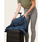 Load image into Gallery viewer, A woman holds a luna blue lap blanket with her suitcase, showing that she is taking it to travel. [4358065671394-7, 4628803738031-5]
