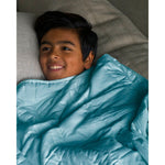 Load image into Gallery viewer, A boy on a sofa with an aqua mini weighted blanket [44385363689691]
