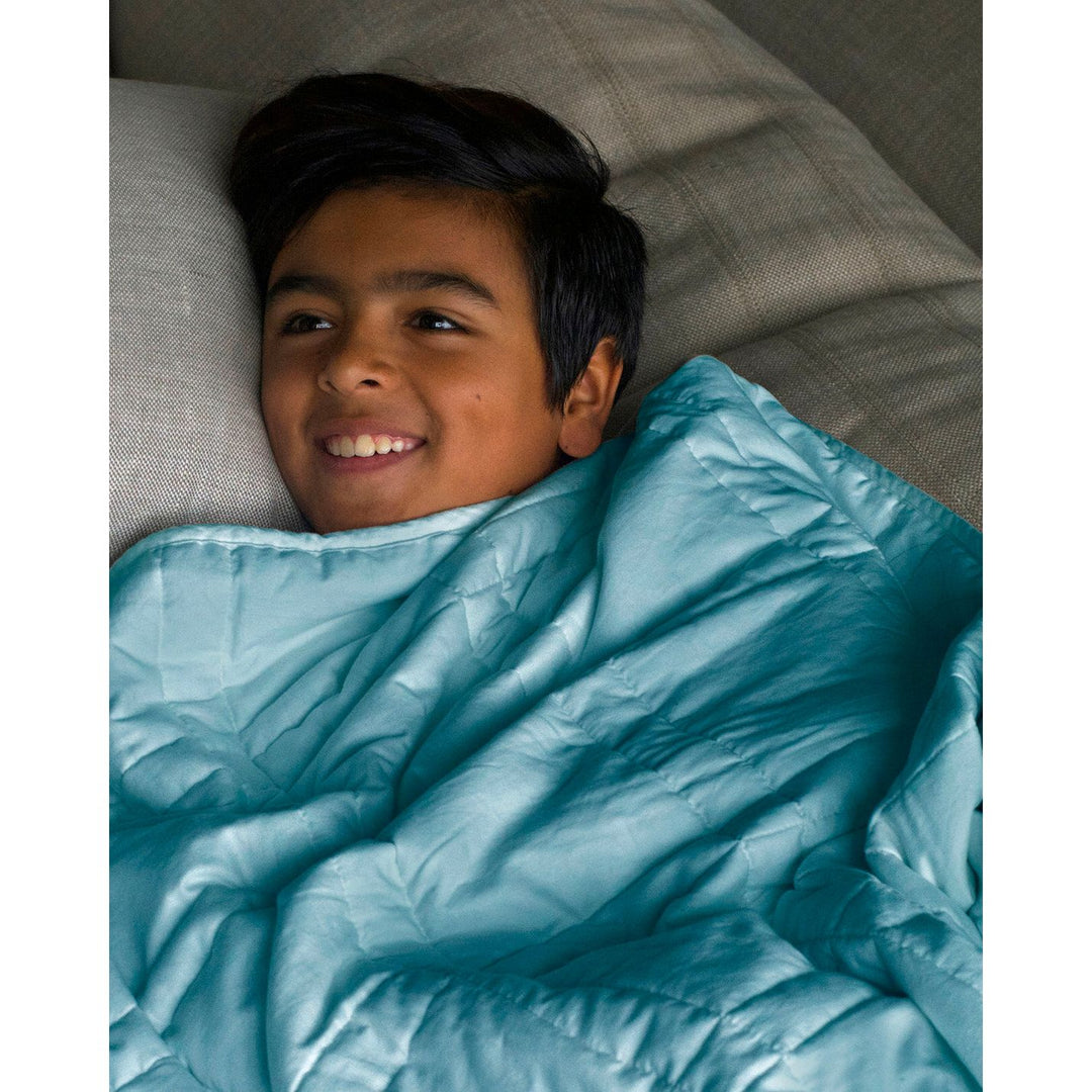 A boy on a sofa with an aqua mini weighted blanket [44385363689691]