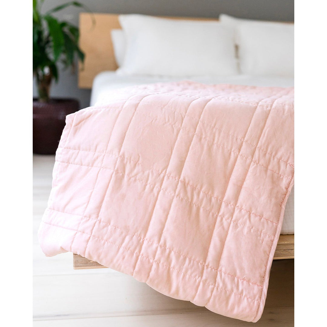 Petal pink weighted blanket on the edge of a bed [44385363656923]