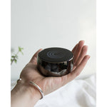 Load image into Gallery viewer, A womans hand holds up a silver speaker against a white wall
