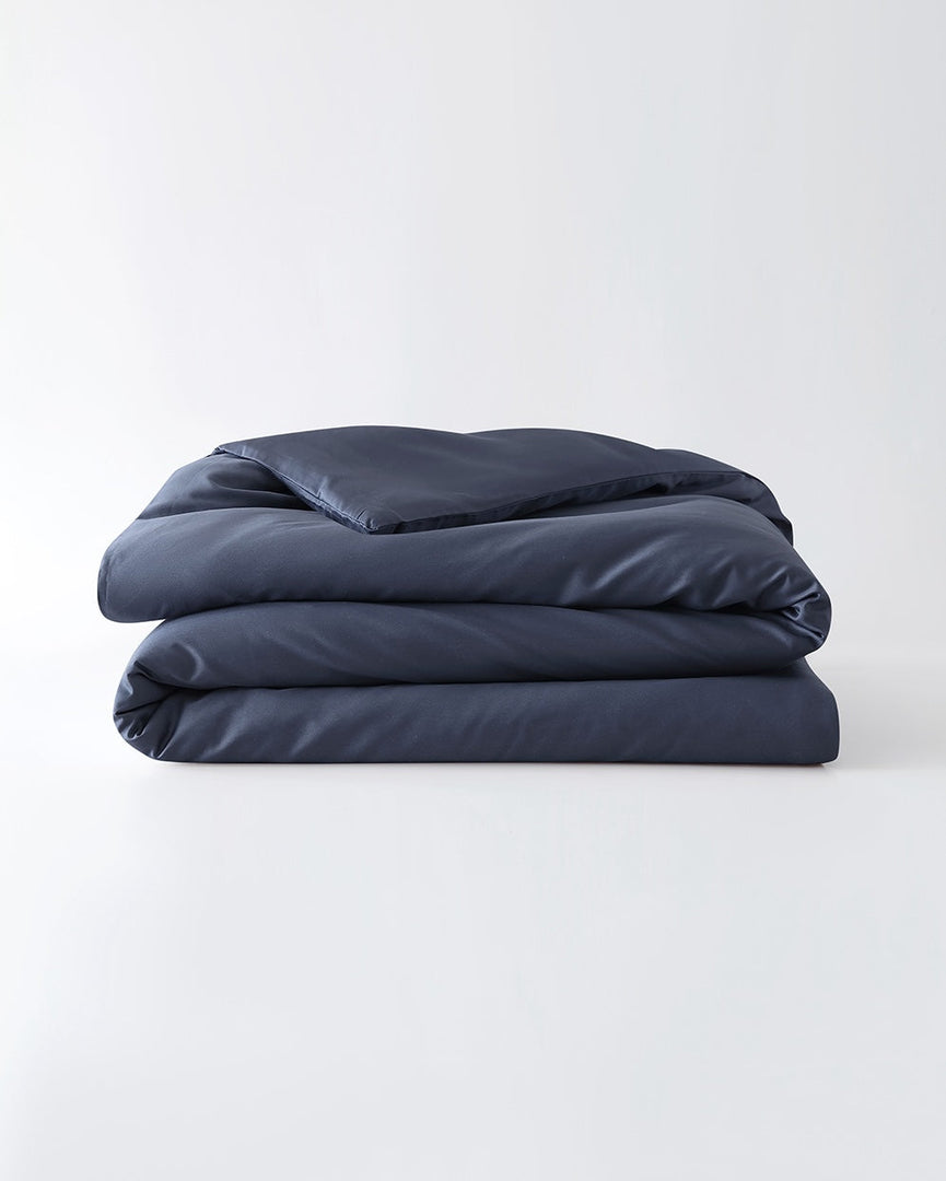 A folded cotton duvet cover in Luna Blue on a blank background [44422682083547, 45027100033243, 46061921763547, 46301205332187, 46063268331739, 46301204938971, 46061921632475, 46061921501403, 46301205201115, 46061921370331, 46301205070043, 46730786668763, 46730786930907, 46730787193051, 46730787455195]