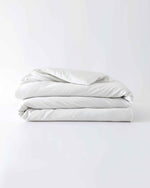 Load image into Gallery viewer, A white cotton duvet cover folded against an empty background [44422681886939,45027099410651,46063267610843,46063267643611,46063267676379,46063267709147,4606326839727546730800627931, 46730800759003, 46730800890075, 46730801021147]
