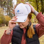 Load image into Gallery viewer, Woman placing a white New Earth hat on her head. 
