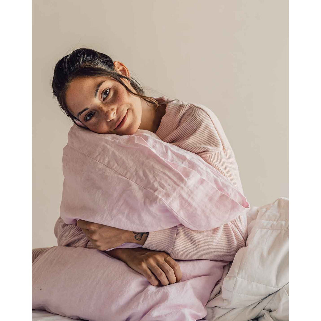 A woman holding a pillow and smiling at the camera. [32783549038672]