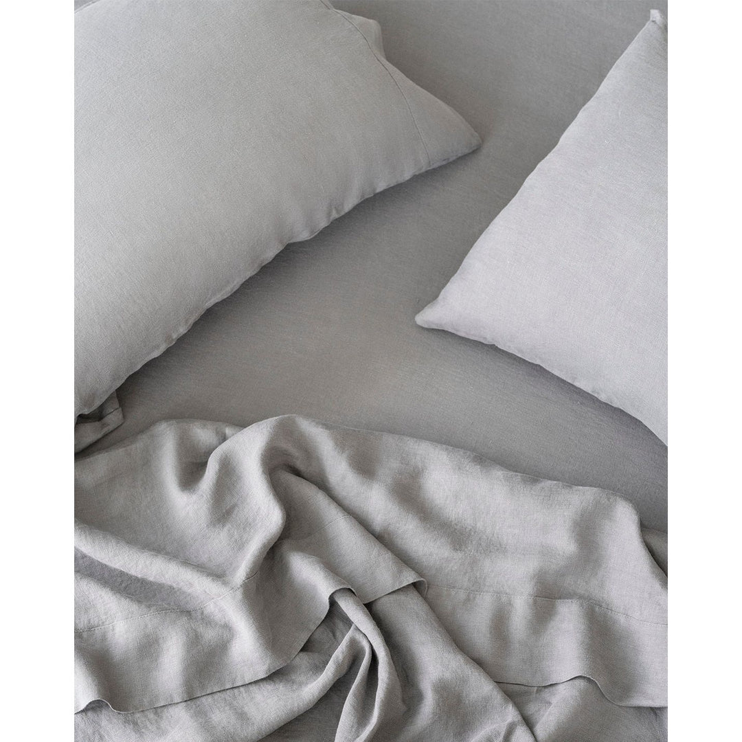 A view from above of rumpled linen sheets and two pillows in dove grey. [32783549136976, 32783549333584]