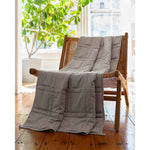 Load image into Gallery viewer, A soft cotton weighted blanket the color silver sage is draped across a chair in a home. [44385233076443, 44385233174747, 44385233240283] 
