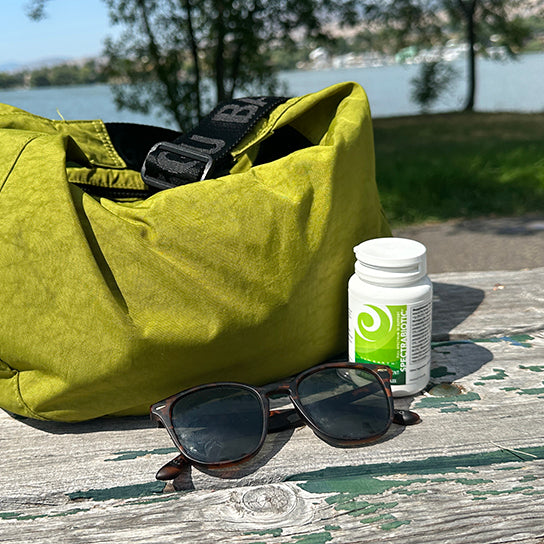 Bottle of New Earth's Spectrabiotic sitting on a worn bench next to a green purse and pair of sunglasses