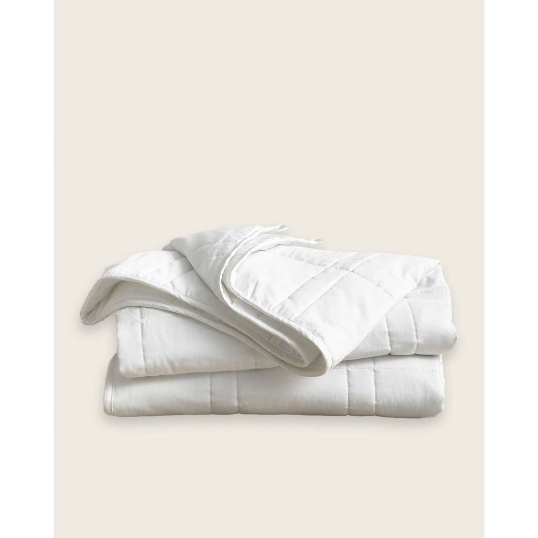 A white cotton weighted blanket is folded on a plain background.  [42934587621595,45574417809627, 45574417940699,45574418071771, 45574418006235]