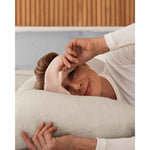 Load image into Gallery viewer, A senior woman with blonde hair lays down on a pillow wearing a pink silk sleep mask, holding one side up to view the camera [44377020825819]
