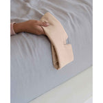 Load image into Gallery viewer, A young woman holds a silk sleep mask in pink off the side of the bed [44377020825819]
