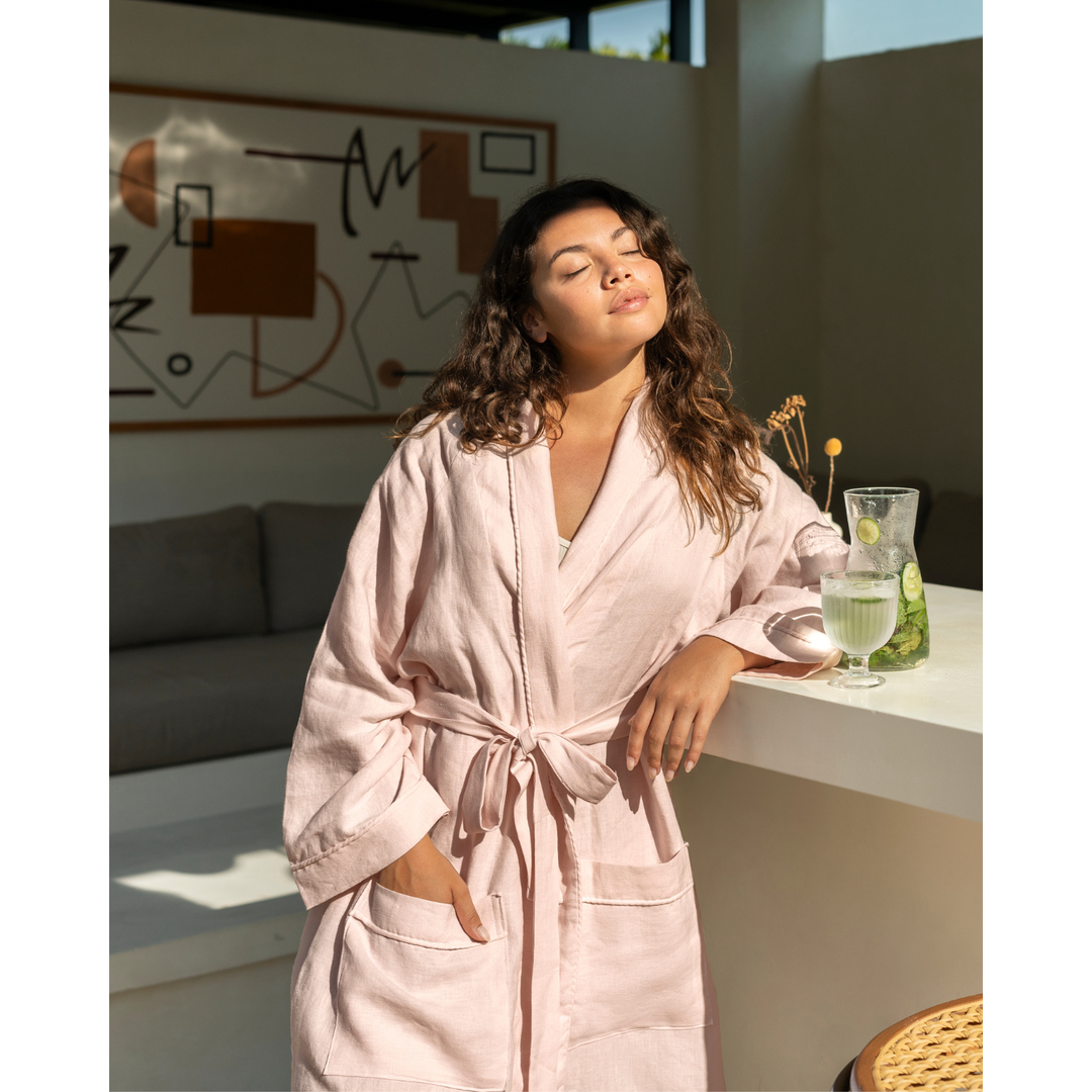 Woman in sunny kitchen wearing blush pink linen robe [45949488201947, 45949488234715]